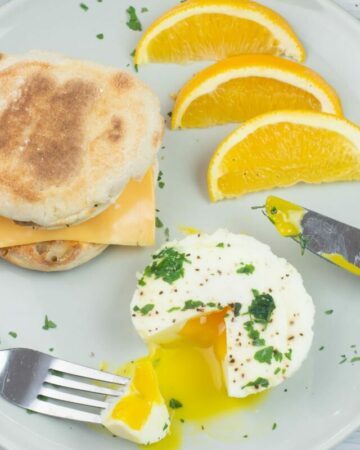 A serving of Instant Pot Poached Eggs on a plate with orange slices.