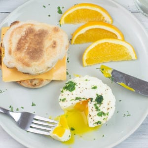 A serving of Instant Pot Poached Eggs on a plate with orange slices.
