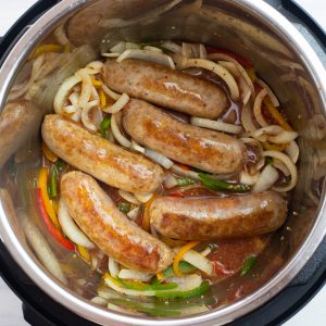 Overhead photo of 5 Italian sausages with sliced peppers and onions
