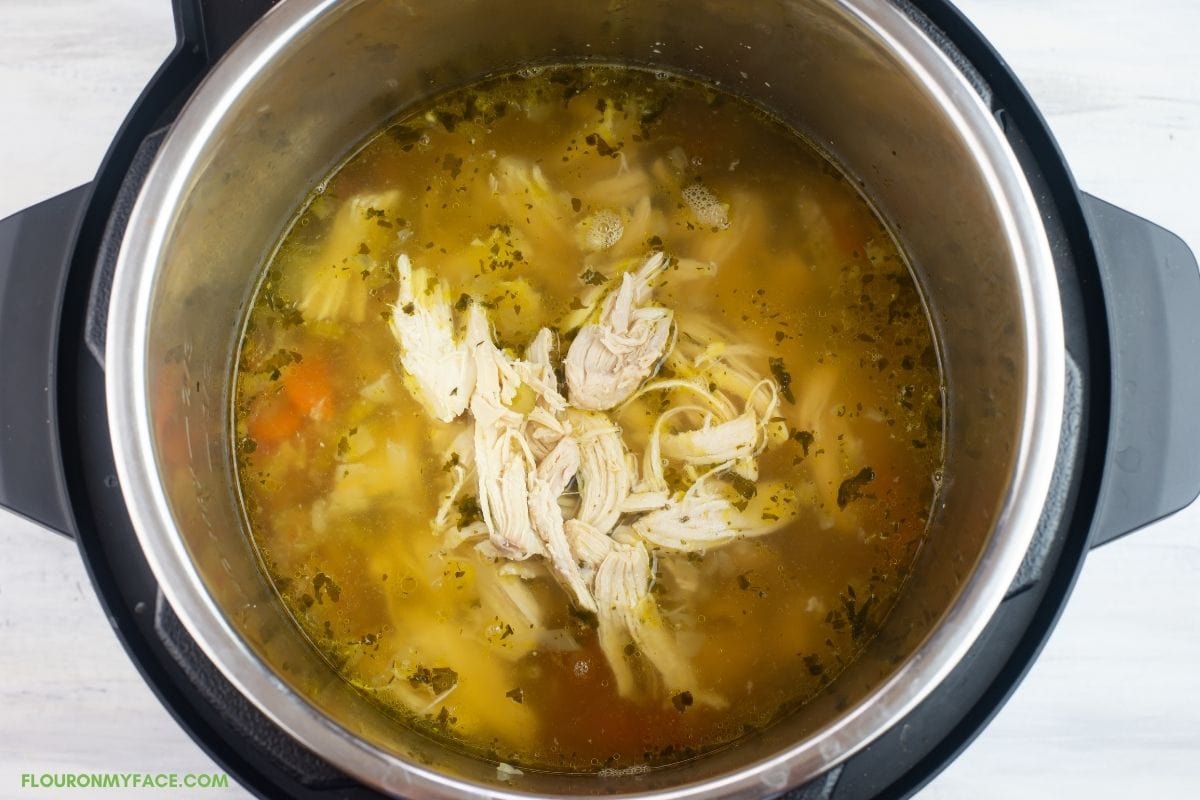 Adding shredded chicken back into the soup pot.