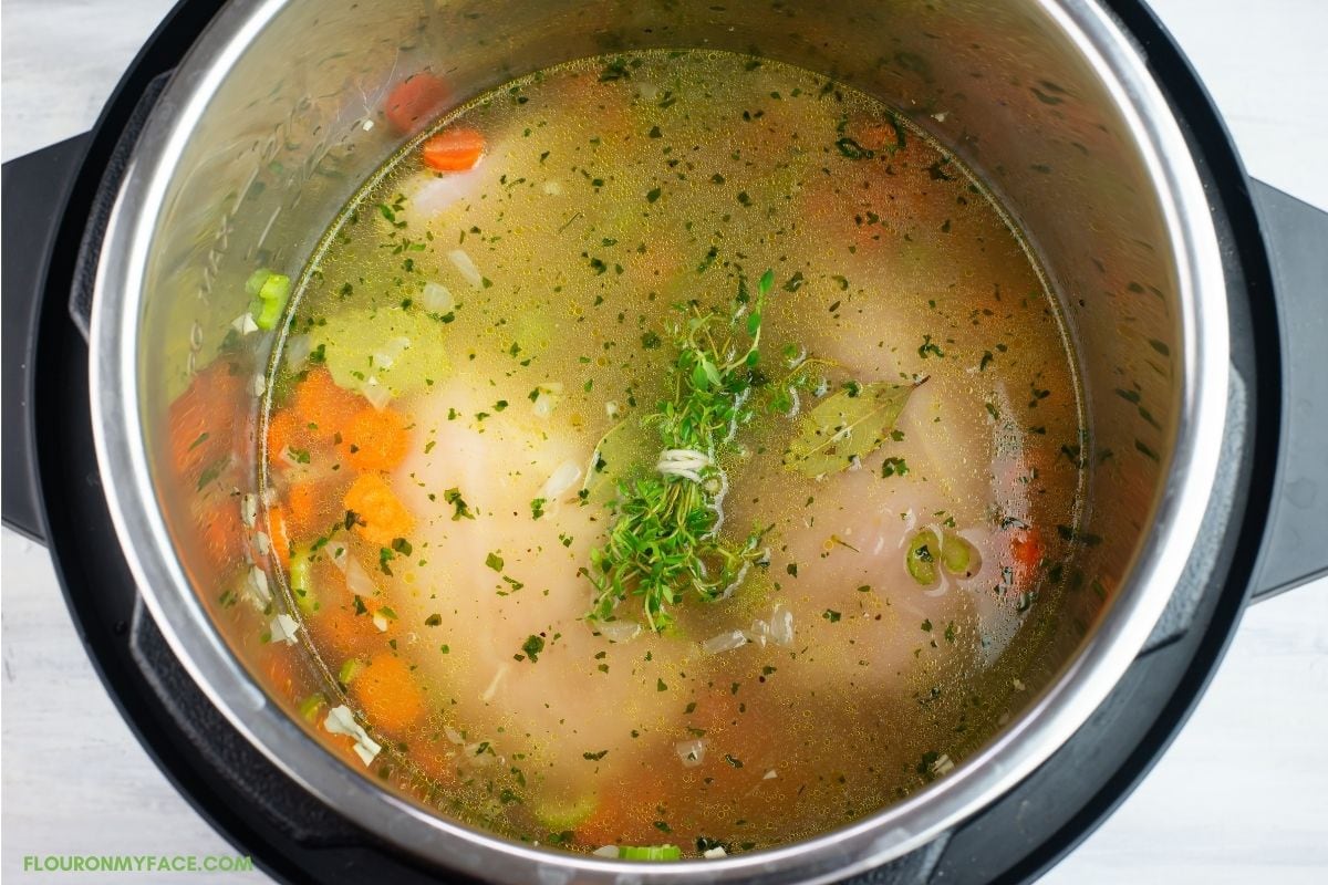 Adding chicken broth to the ingredients in the pot.