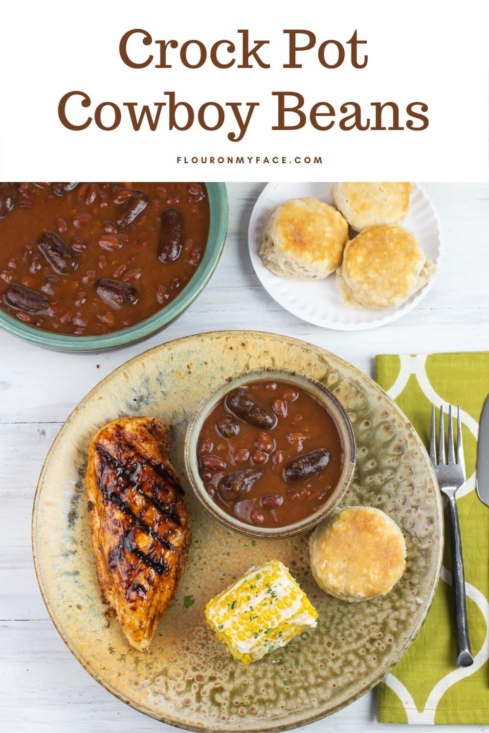 A plate with grilled chicken, corn, biscuit and a small serving bowl of Crock Cowboy Beans 