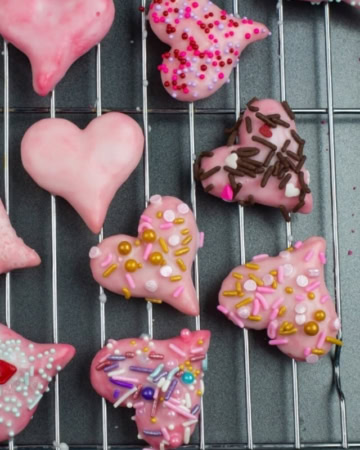 Valentines Day Spritz Cookies decorated with a sugar glaze and red, pink and gold holiday sprinkles