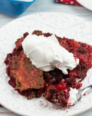 A serving of red velvet dump cake topped with whipped cream.