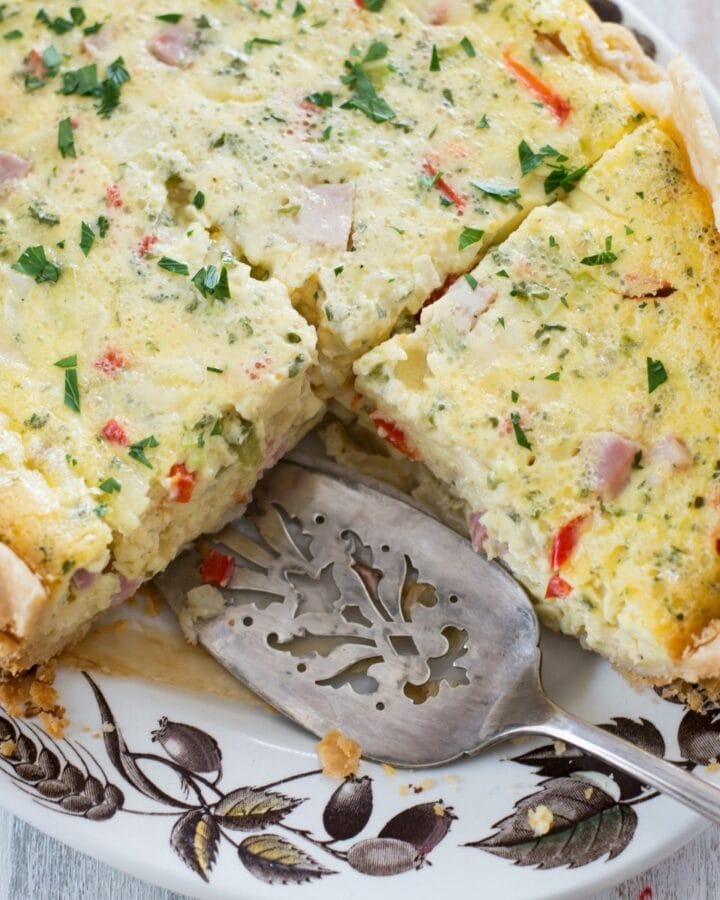 Breakfast Quiche on a serving platter with a slice cut out.