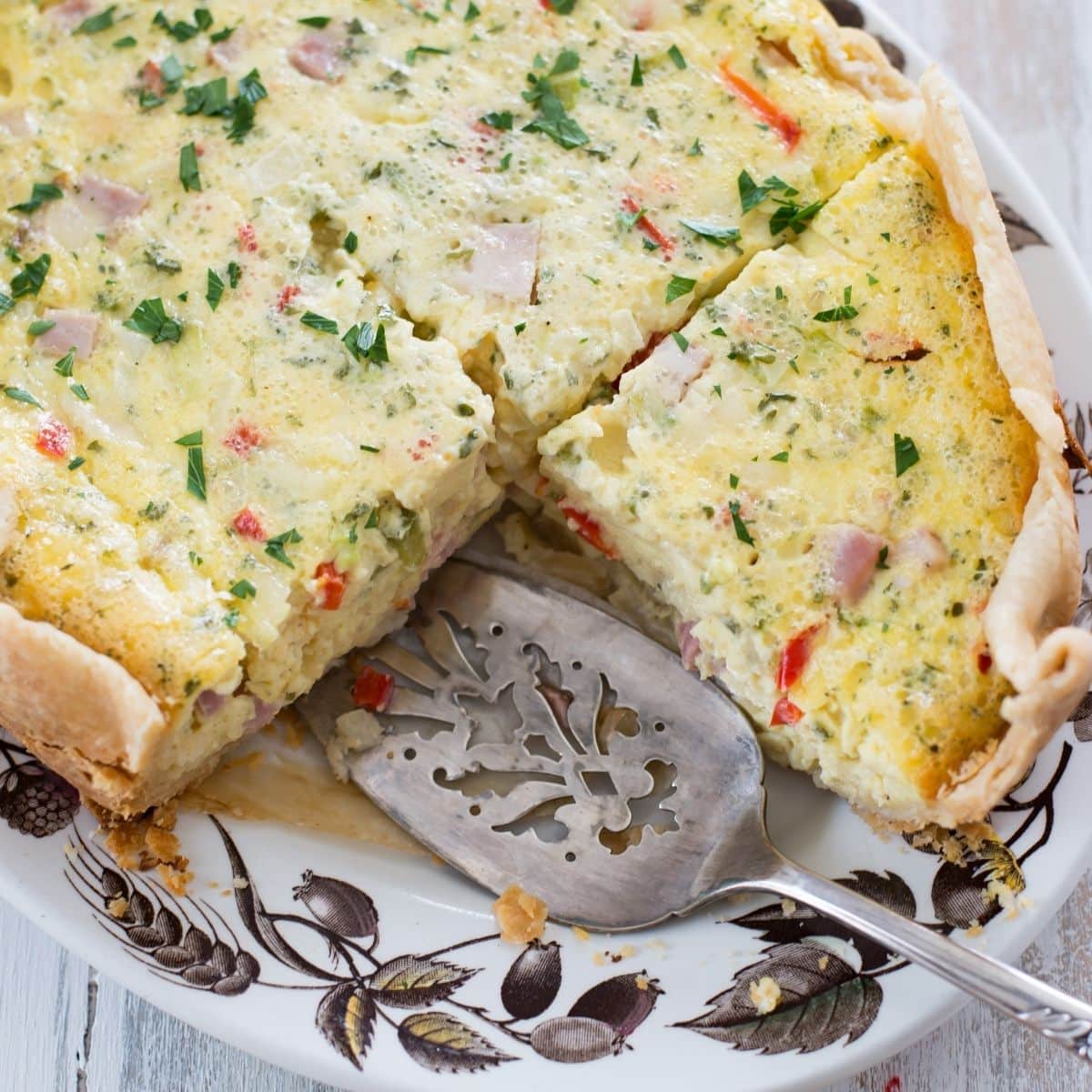 Breakfast Quiche on a serving platter with a slice cut out.