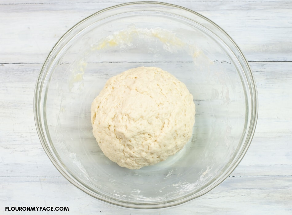 a ball of sourdough pizza dough as it rests in a bowl