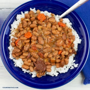 Crock Pot Pinto Beans served over white rice in a blue bowl with a blue cloth napkin