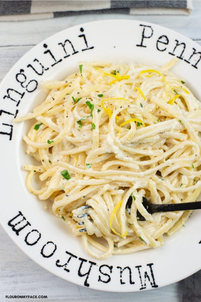 a pasta bowl filled with a serving of creamy Lemon Alfredo Sauce over linguine pasta