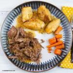 London Broil with vegetables and homemade gravy on a dinner plate.