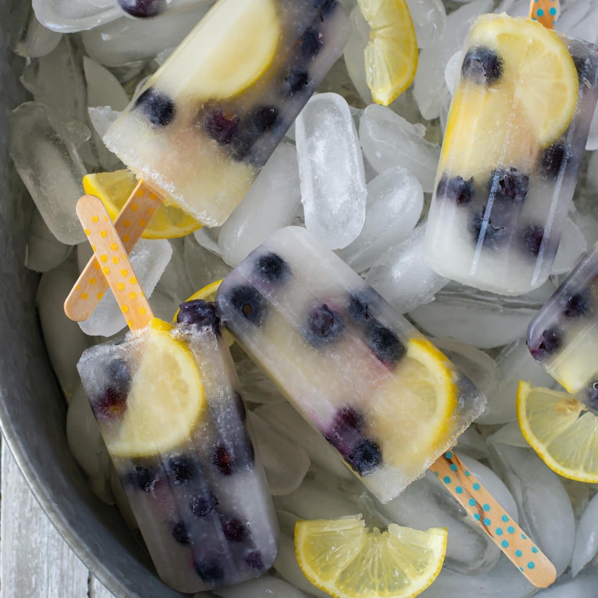 Homemade ice pops in a tin serving tray stacked on a bed of ice cubes.