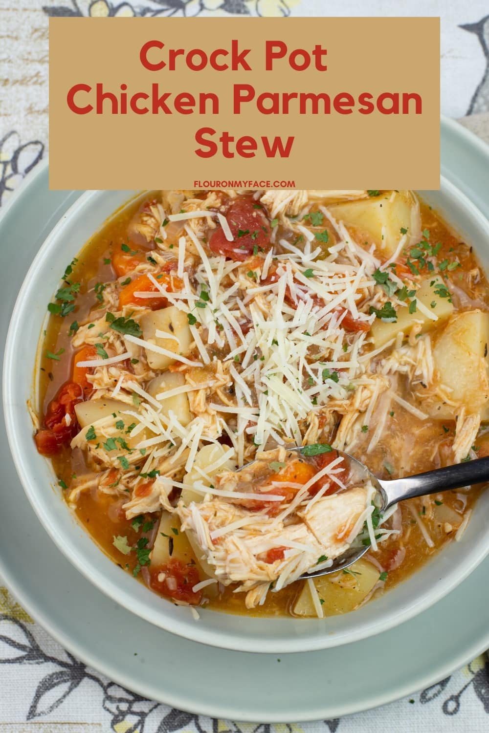 Chicken Stew in a grey bowl, topped with shredded Parmesan cheese on a cloth place mat.