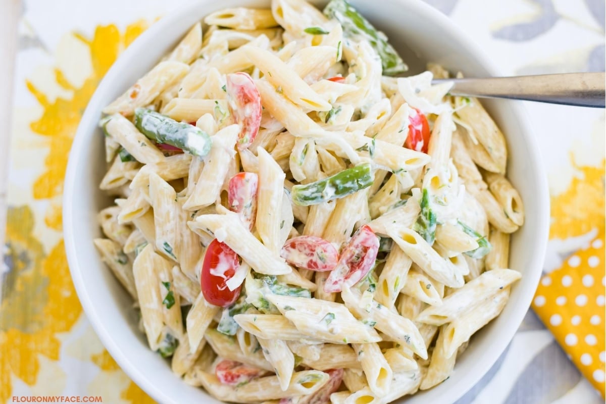 Summer pasta salad made with summer vegetables in a white bowl