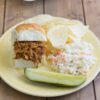 Coke Cola Sliders served with coleslaw and chips on a plate.