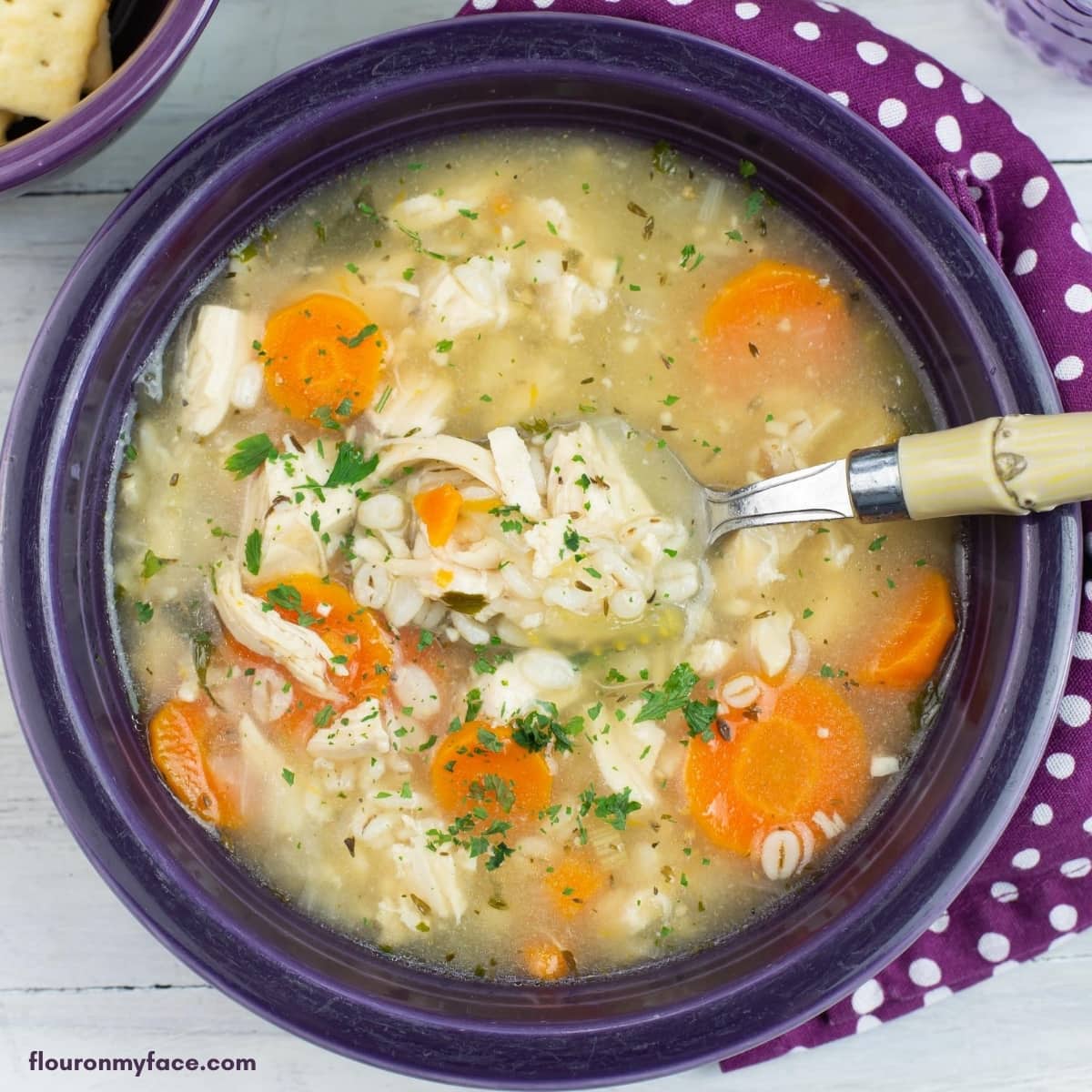 A purple glass bowl filled with Instant Pot Chicken Barley Soup