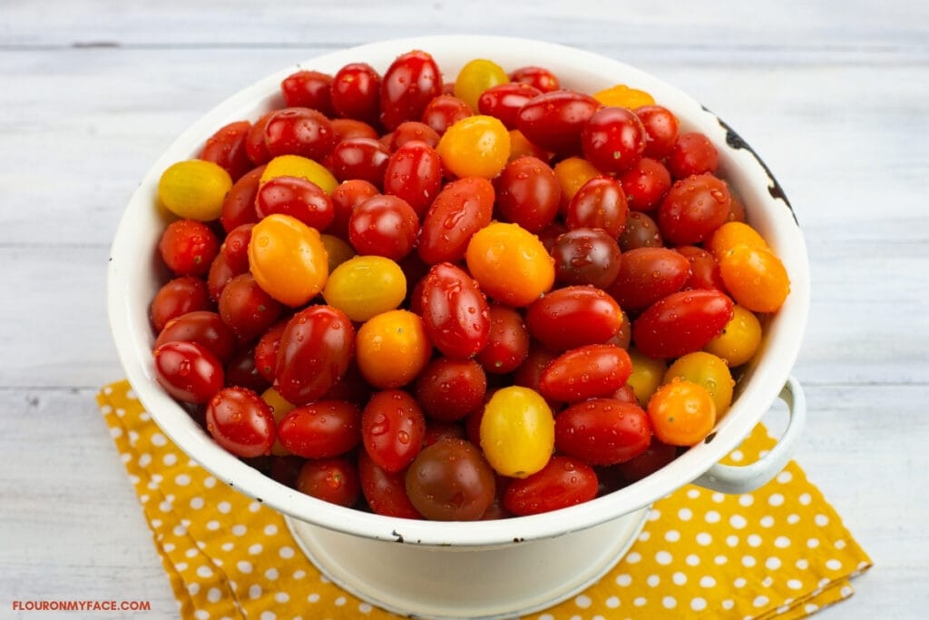 white colander filled with ripe heirloom grape tomatoes