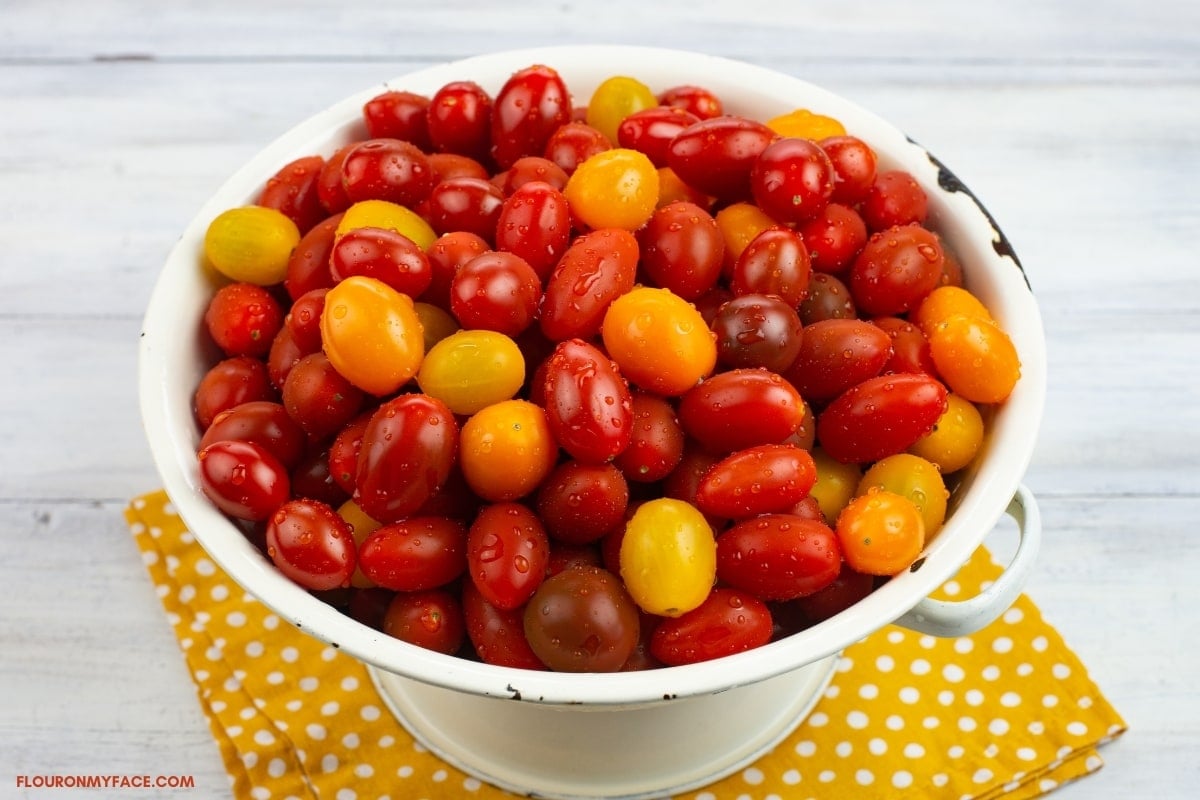 white colander filled with ripe heirloom grape tomatoes.