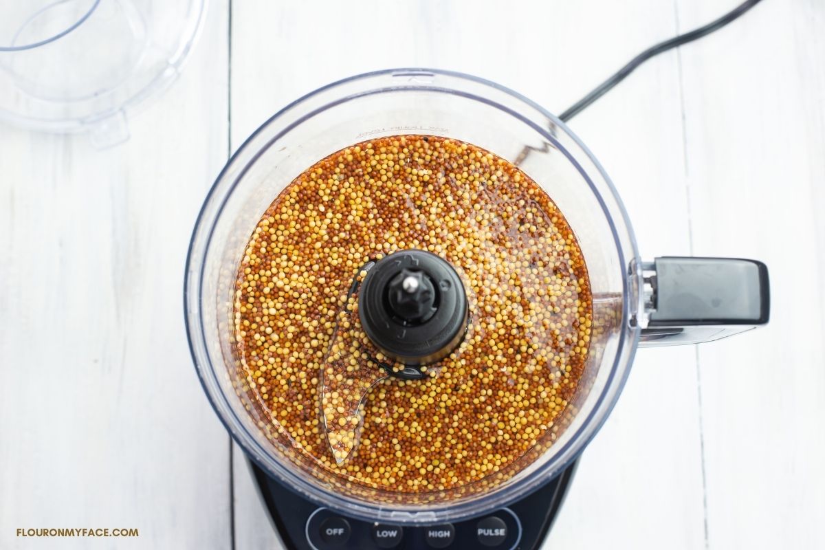 Overhead photo of a food processor  filled with Dijon mustard ingredients before blending