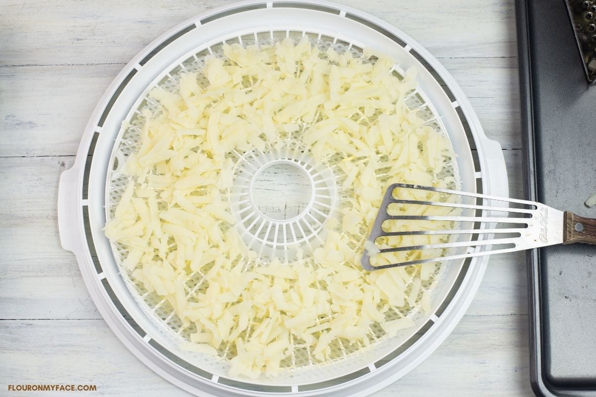 a round dehydrator tray filled with shredded potatoes