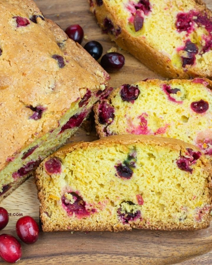 Cranberry bread slices on a wooden cutting board.