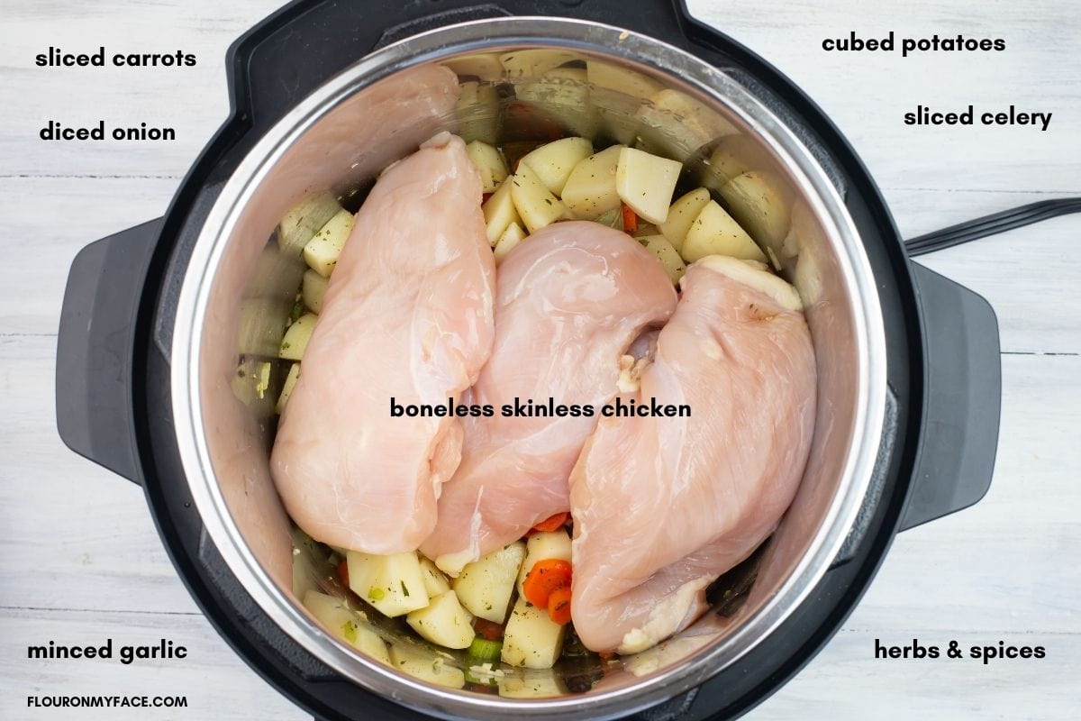 Three boneless skinless chicken breasts ontop of the vegetables in an Instant Pot.