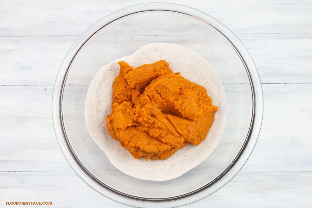 Pumpkin puree added to a bowl of sugar and pie spices.