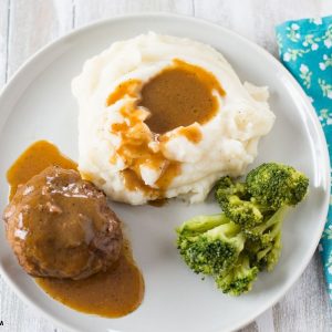 Salisbury Steak with gravy, mashed potatoes and broccoli on a grey plate