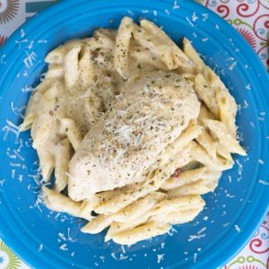 A piece of Chicken Alfredo on a plate of pasta.