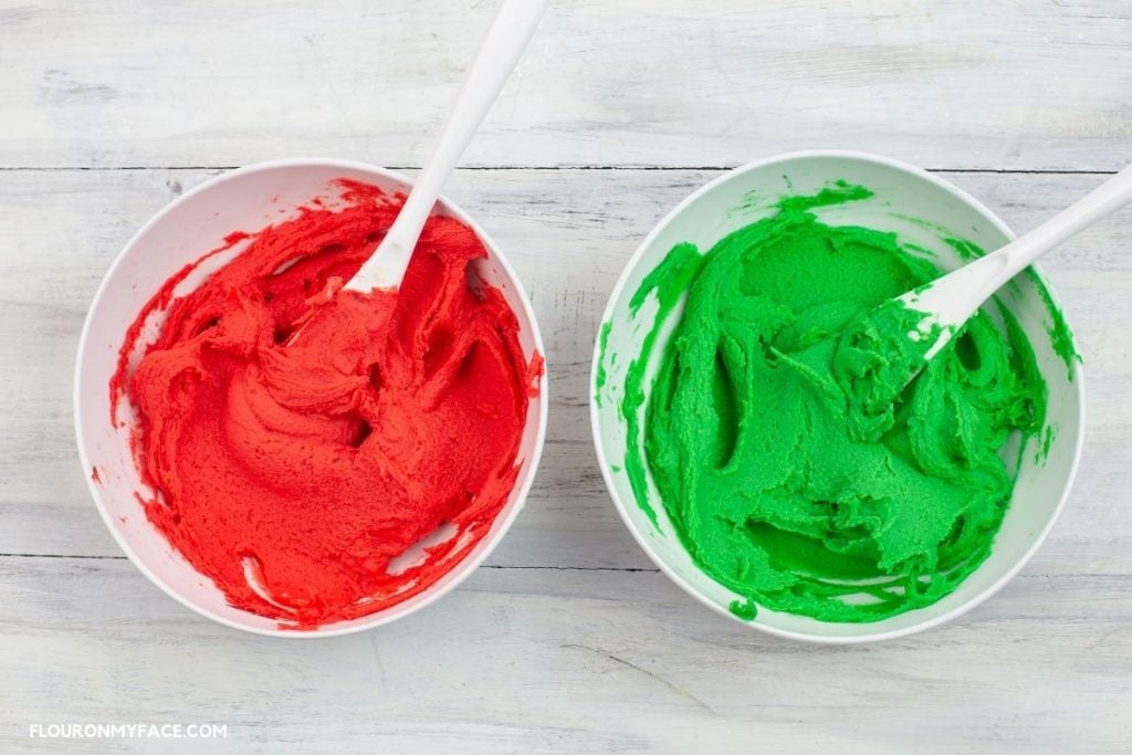 red and green colored spritz cookie dough in small bowls.