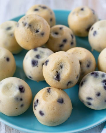 Pile of blueberry muffin bites on a blue glass plate.
