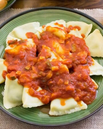 Ravioli topped with homemade garden vegetable sauce. on a dinner plate