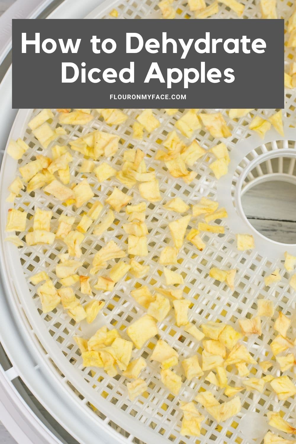 Long vertical image of dried diced apple pieces on a dehydrator tray.