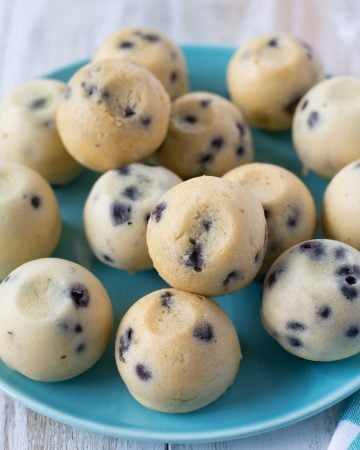 Pile of blueberry muffin bites on a blue glass plate.