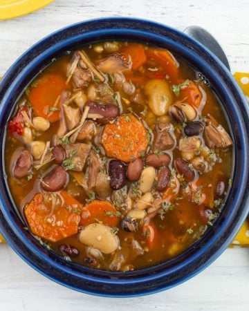 A blue bowl filled with turkey and bean soup.