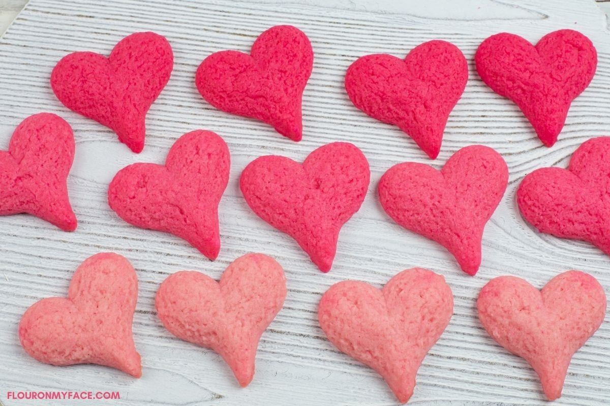 Pink Ombre heart shaped cookies on a white wooden board.