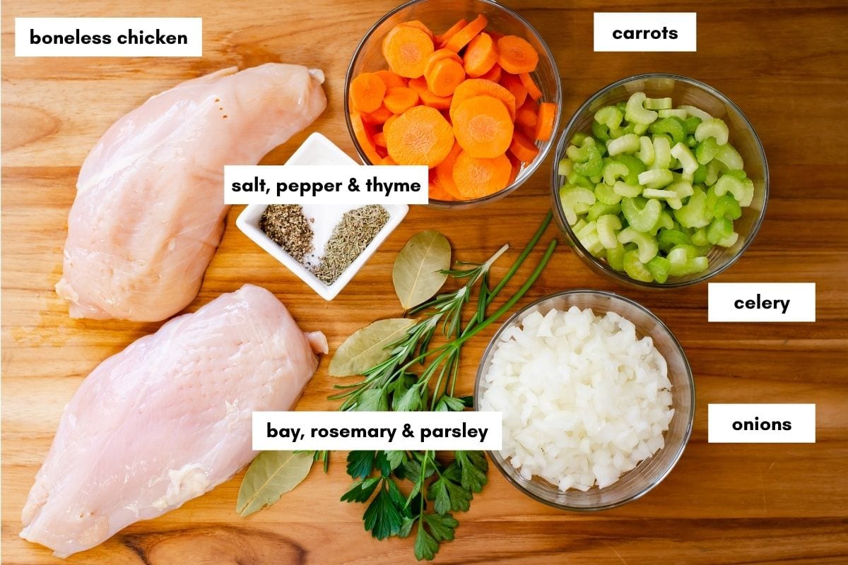 Chicken noodle soup ingredients on a wooden cutting board.
