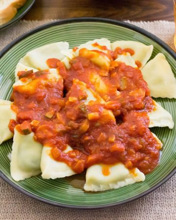 Ravioli topped with homemade garden vegetable sauce. on a dinner plate