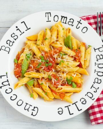 Pasta bowl filled with noodles tossed with cherry tomato sauce.