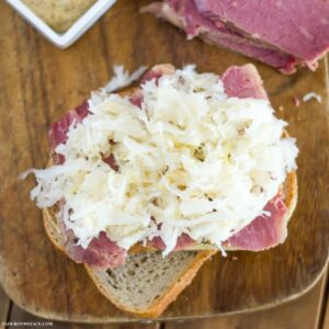Making a sandwich of corned beef on rye bread topped with sauerkraut.