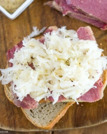 Making a sandwich of corned beef on rye bread topped with sauerkraut.