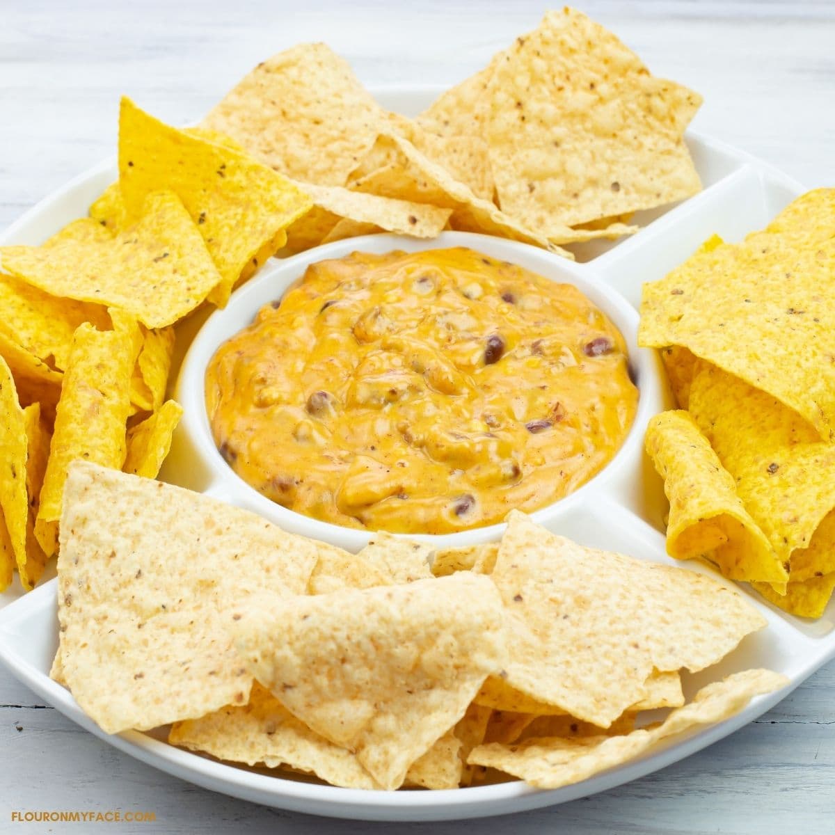 Chili Cheese Dip in a white serving dish with flour and corn chips.