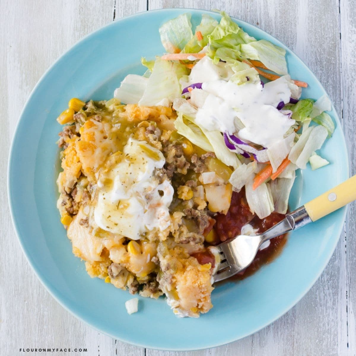 Overhead bowl filled with cornbread casserole with toppings.