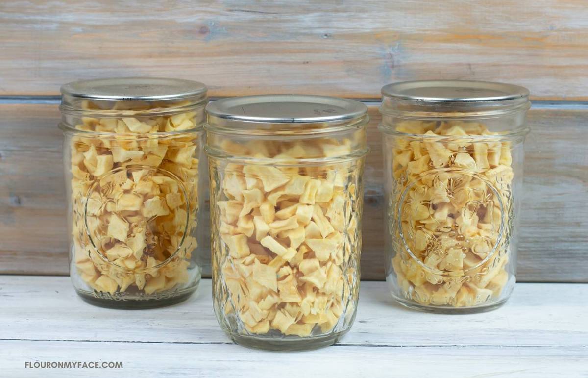 Dried diced apple pieces in glass mason jars.