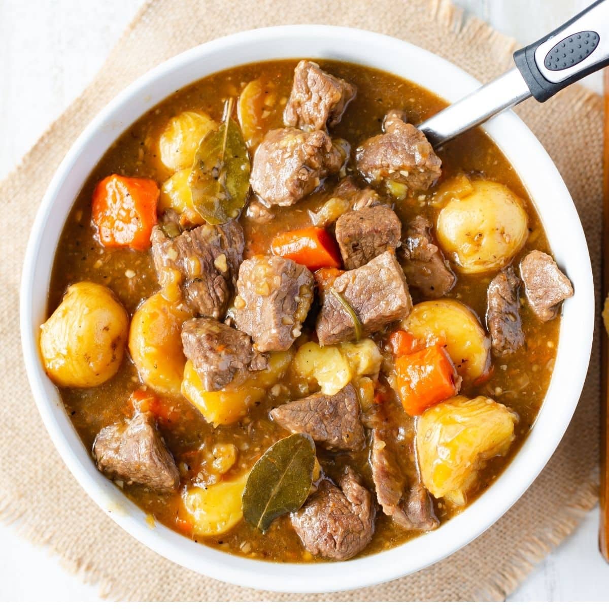 A white serving bowl filled with beef stew.