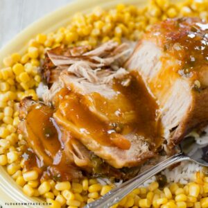 Pork loin with apricot glaze served with corn on a platter.