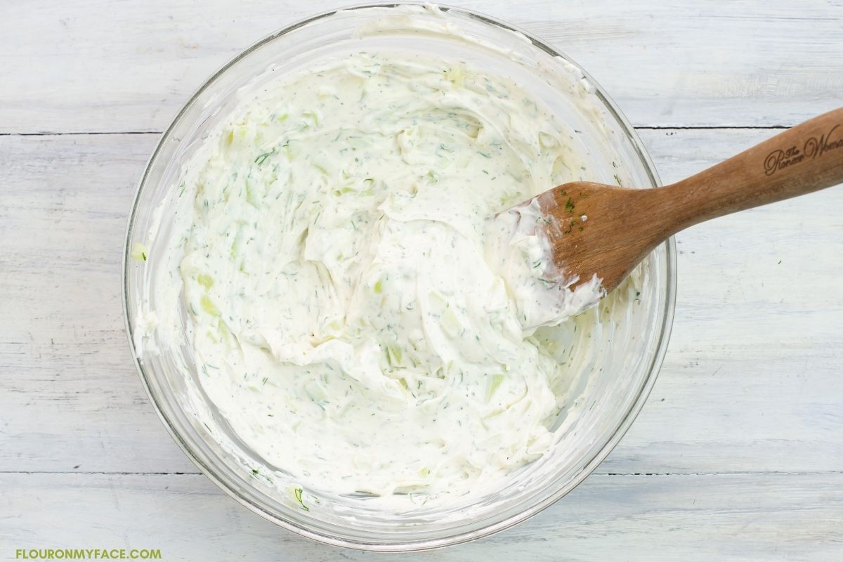 Cucumber dip ingredients mixed together in a glass bowl.
