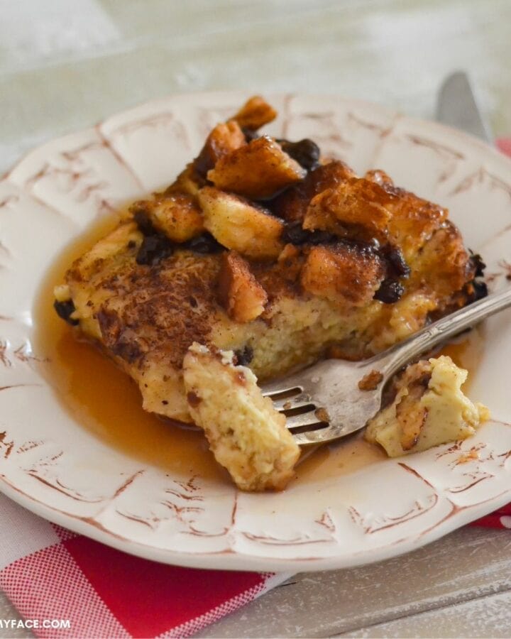 Closeup photo of a square piece of eggnog French toast with syrup on a plate.