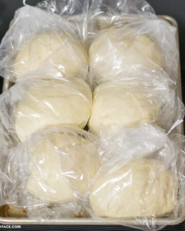 Bags of pizza dough on a sheet pan ready to go into the freezer.
