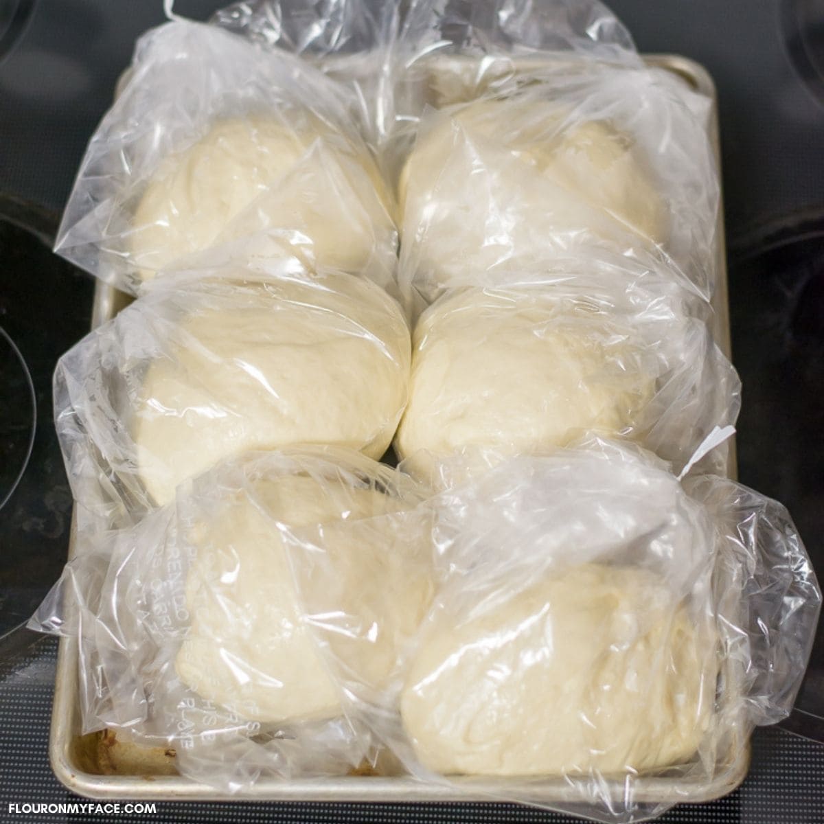 Bags of pizza dough on a sheet pan ready to go into the freezer.