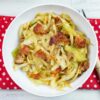 A white bowl filled with fried cabbage topped with crispy bacon pieces.